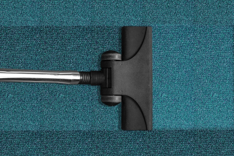A vacuum cleaner head on a teal carpet