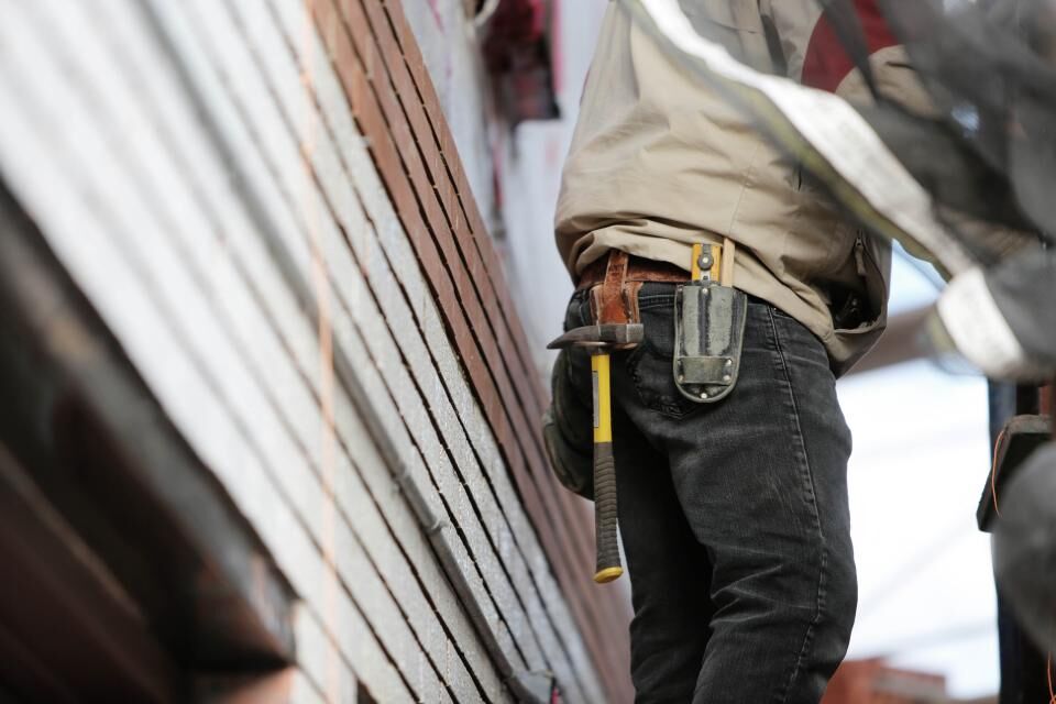 A worker with a hammer and tape measure on a tool belt