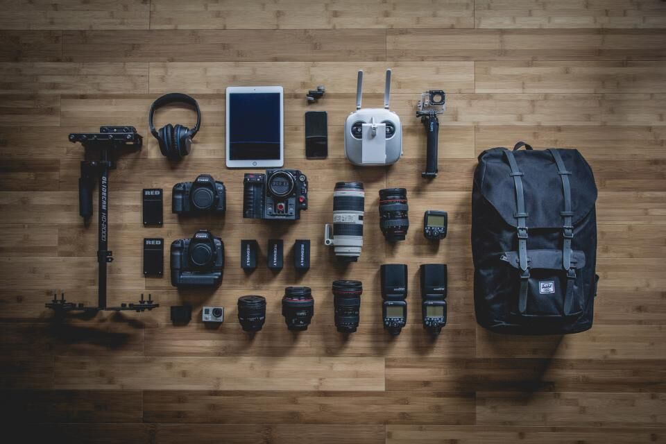 Cameras, lenses, a stabilizer and a backpack laid out on a wooden floor