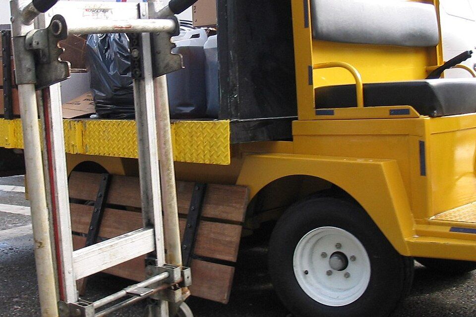 A hand truck leaning against a small delivery vehicle